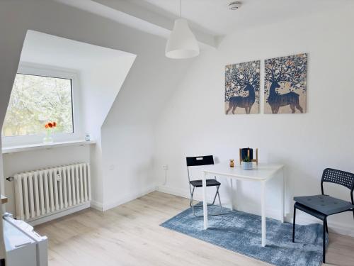 ein weißes Wohnzimmer mit einem Schreibtisch und einem Fenster in der Unterkunft Möbliertes Apartment in Bochum-nahe Jahrhunderthalle in Bochum
