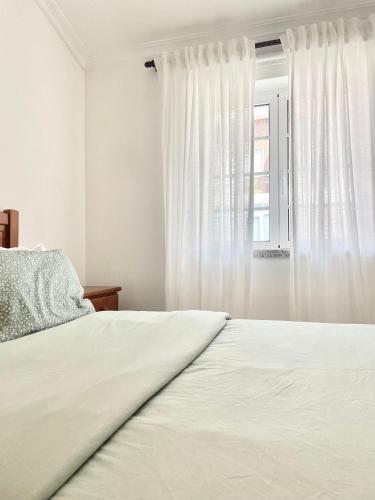 a white bedroom with a bed and a window at Sabugal Comfort - Central Castelo in Sabugal