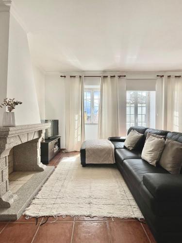 a living room with a black couch and a fireplace at Sabugal Comfort - Central Castelo in Sabugal