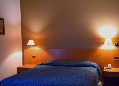 a bedroom with a blue bed and two lights on the wall at Hotel 90 in Capurso