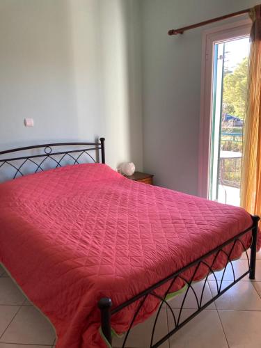 a bed with a red comforter in a room with a window at Ammodares in Lixouri