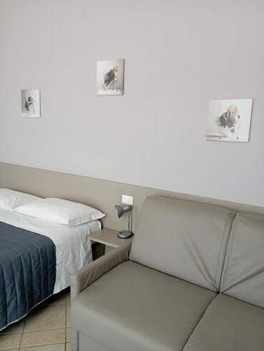 a white bedroom with a bed and a chair at Camere Girasole in Lazise
