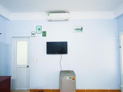 a room with a white wall with a tv on it at Nhà Nghỉ Kiên Cường - Kien Cuong Hostel in Cat Ba