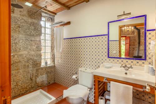 a bathroom with a sink and a toilet and a mirror at Casa da Benfeitoria in Guimarães
