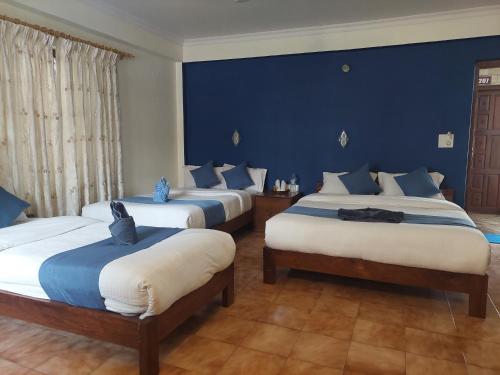 a bedroom with three beds with blue walls at Blue Planet Lodge & Restaurant in Pokhara