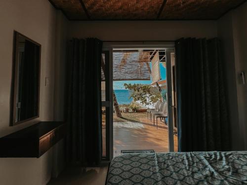 a bedroom with a door leading to a beach at Gloria's Beach House in Oslob