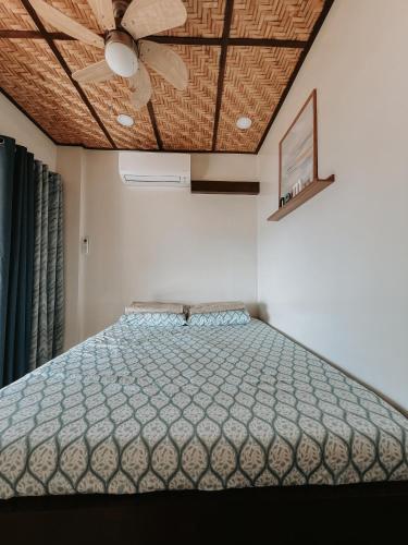 a bedroom with a bed with a ceiling fan at Gloria's Beach House in Oslob