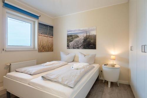 un letto bianco in una stanza con una finestra di Haus-Ostseeapartments-am-Fehmarnsund-Wohnung-27-Strandrubin a Grossenbrode