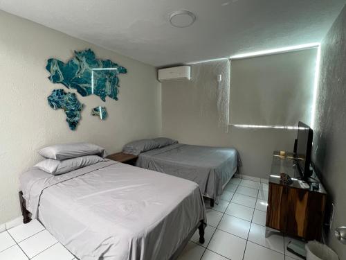 a room with two beds and a tv in it at Casa Petfriendly Bosque de la Primavera in Guadalajara