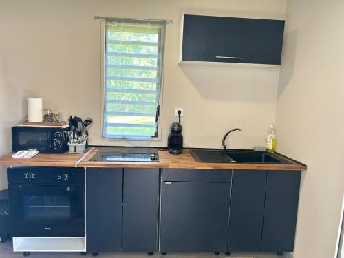 馬羅尼河畔聖羅蘭的住宿－JEALYA TOURISTIQUES，厨房配有蓝色橱柜、水槽和窗户。