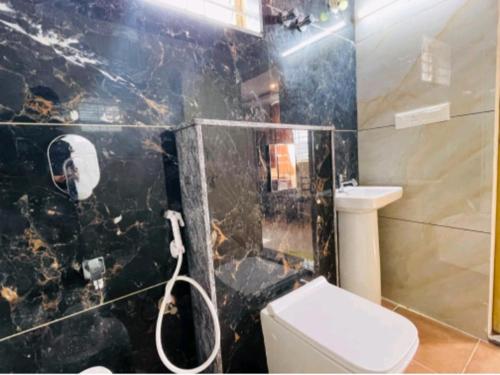 a bathroom with a toilet and a black marble wall at Yashaswiny recidency in Mysore