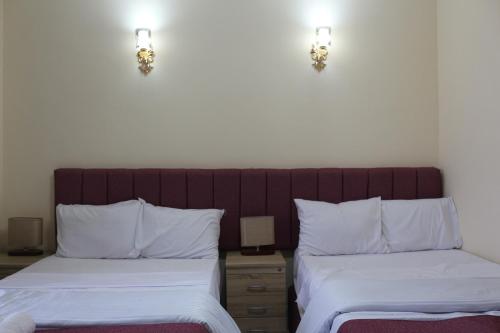 a bedroom with two beds and two lights on the wall at pyramita luxury hotel in ‘Ezbet `Abd el-Ḥamîd