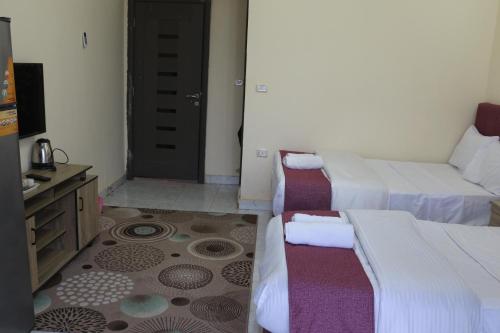 a hotel room with two beds and a television at pyramita luxury hotel in ‘Ezbet `Abd el-Ḥamîd