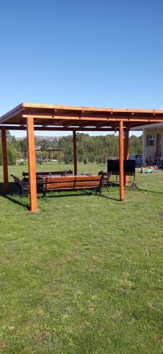 a wooden pavilion with benches in a field at Cabaña El Cardenal in Tandil