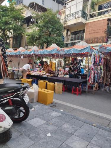 um mercado com uma moto estacionada em frente em H2_Homestay phố cổ _Check in tự động em Hanói