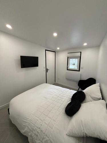 une chambre avec un grand lit blanc et une télévision dans l'établissement Welcome to the black and White, à Villepinte