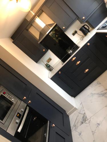 a kitchen with black cabinets and marble counter tops at Stunning 2 bedroom apartment in Preston