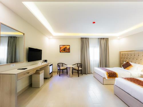 a hotel room with a bed and a desk with a television at Petra Premium Hotel in Wadi Musa