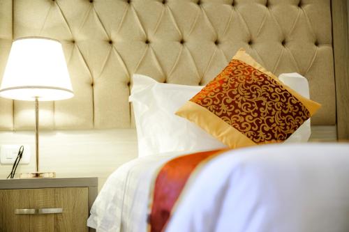 a bedroom with a bed with a headboard and a lamp at Petra Premium Hotel in Wadi Musa