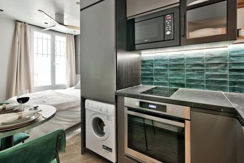 Il comprend une cuisine équipée d'une cuisinière. four supérieur à côté d'une table dans l'établissement NEW ! Cosy Suite Intimate Nest Sacré Coeur Paris !, à Paris