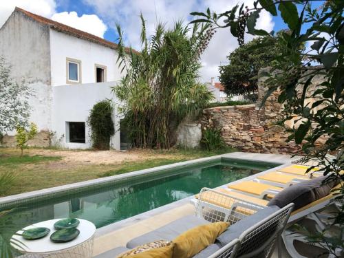 a pool with two lounge chairs next to a house at Farmacia Beach House in Odemira
