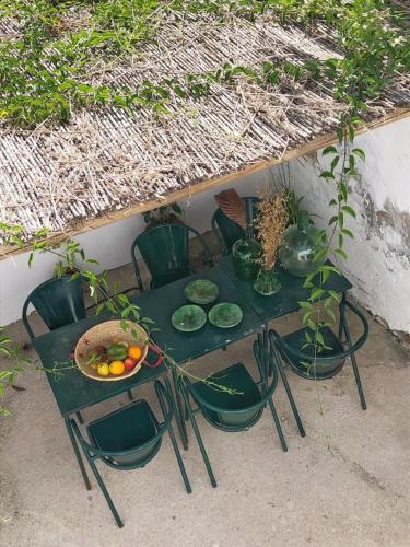 a green table with chairs and a bowl of fruit on it at Farmacia Beach House in Odemira