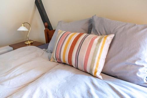 a bed with a striped pillow on top of it at Møllehusets Bed & Breakfast in Nordborg