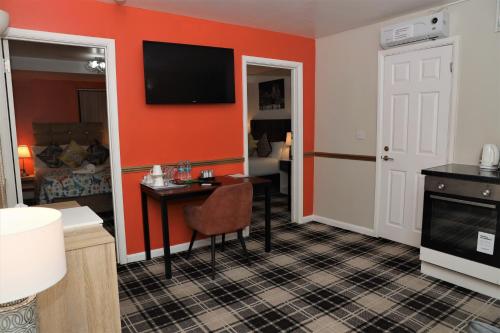 a room with a desk and a tv on a wall at 4 Sisters Inn in Theydon Bois