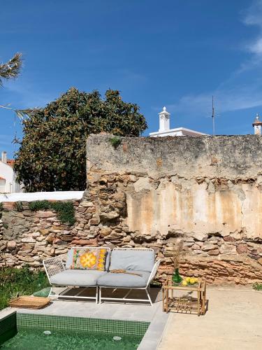 a couch sitting in front of a stone wall at Farmacia Beach House in Odemira