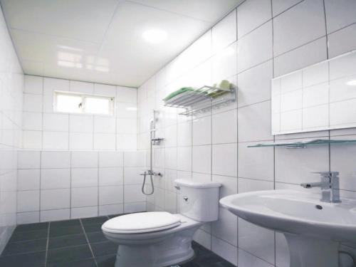 a white bathroom with a toilet and a sink at Double Lake B&B in Zhushan