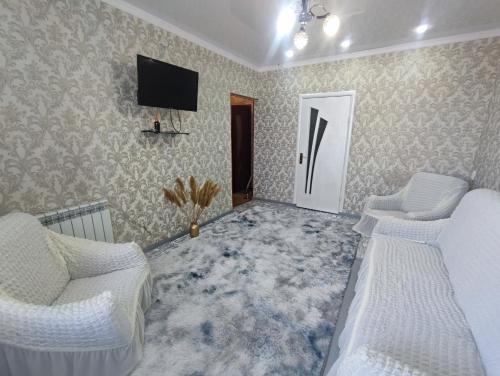 a living room with two beds and a flat screen tv at Уютная квартира in Taraz