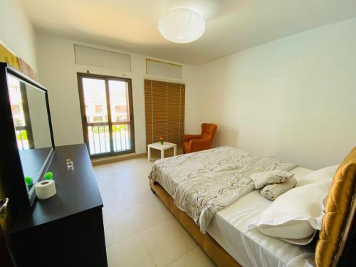 a bedroom with a bed and a desk and window at Tala bay aqaba one bedroom nice view in Al Burj