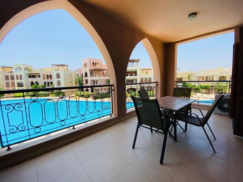 einen Balkon mit einem Tisch und Stühlen sowie Poolblick in der Unterkunft Tala bay aqaba one bedroom nice view in Al Burj