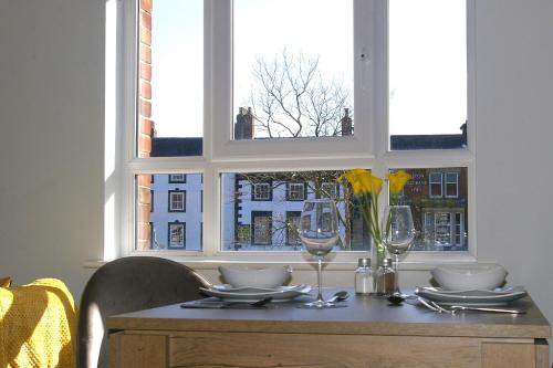 里彭的住宿－The Hornblower Suite - Yorkshire Accommodates，一张桌子,上面有盘子和玻璃杯,还有窗户