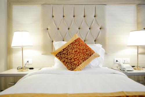 a bedroom with a large white bed and two lamps at Petra Premium Hotel in Wadi Musa
