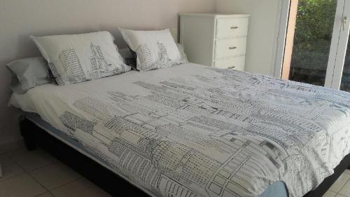 - un lit avec une couette et des oreillers blancs dans l'établissement Maison cosy avec piscine, à Saleilles