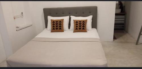 ein weißes Bett mit drei Kissen darauf in der Unterkunft Sahan Villa in Sri Jayewardenepura Kotte