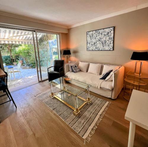 een woonkamer met een bank en een glazen tafel bij Superbe appartement avec Terrasse Jardin et Parking privé in Saint-Tropez