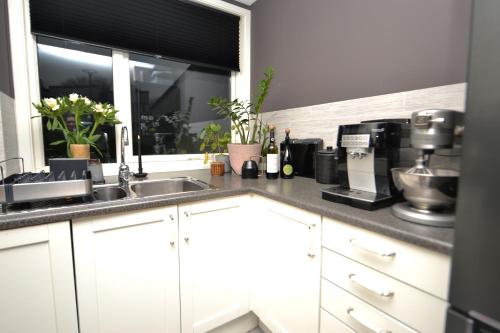 d'une cuisine avec des placards blancs, un évier et une fenêtre. dans l'établissement Private room in Hundvåg, à Stavanger