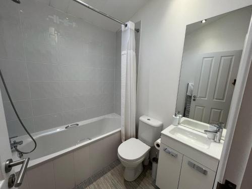 a bathroom with a toilet and a tub and a sink at Remarkable 3-Bed Lodge in Honiton in Honiton