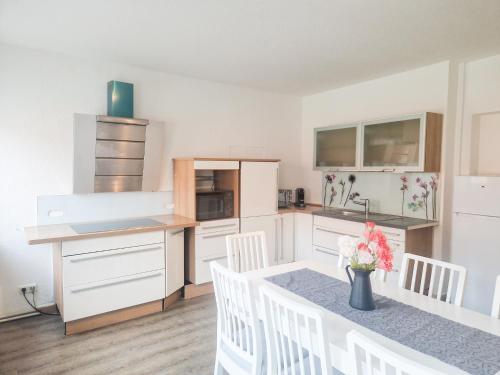 una cocina con armarios blancos y una mesa con sillas blancas. en Apartment am Dammtor, en Hildesheim