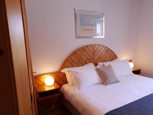 een slaapkamer met een bed met witte kussens en 2 lampen bij Val Colla B&B in Lugano