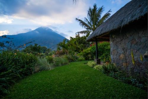 a stone house with a grass yard and a mountain at Hotel Bambu in Santiago Atitlán
