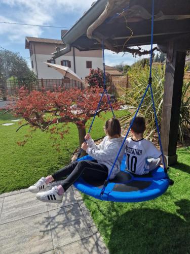 two people sitting on a swing in a yard at The Lake - Casa Vacanza in Dormelletto