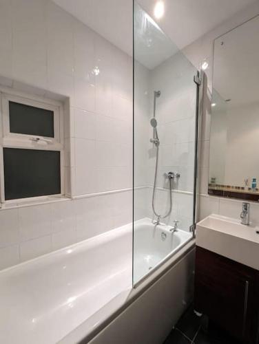 y baño con ducha, bañera y lavamanos. en Cozy 2 Beds Brentwood Flat en Brentwood