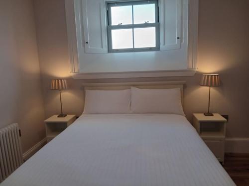 a bedroom with a white bed with two lamps at St Johns old Schoolhouse in Lecarrow