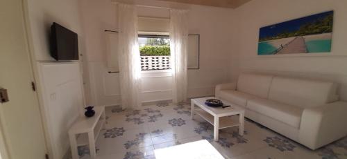 een woonkamer met een bank en een raam bij Il Sole e l'Azzurro in Marina di Lizzano