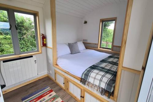 a small bedroom with a bed and two windows at Shepherd's View in Ross on Wye