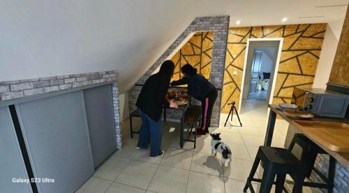dos personas de pie en una mesa en una cocina con un perro en MADAME, en Clérey