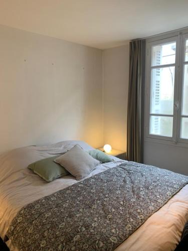 a bed in a bedroom with a window at Normandy chérie in Trouville-sur-Mer
